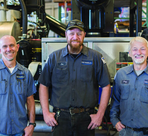Three MetroQuip employees smiling in front of some equipment